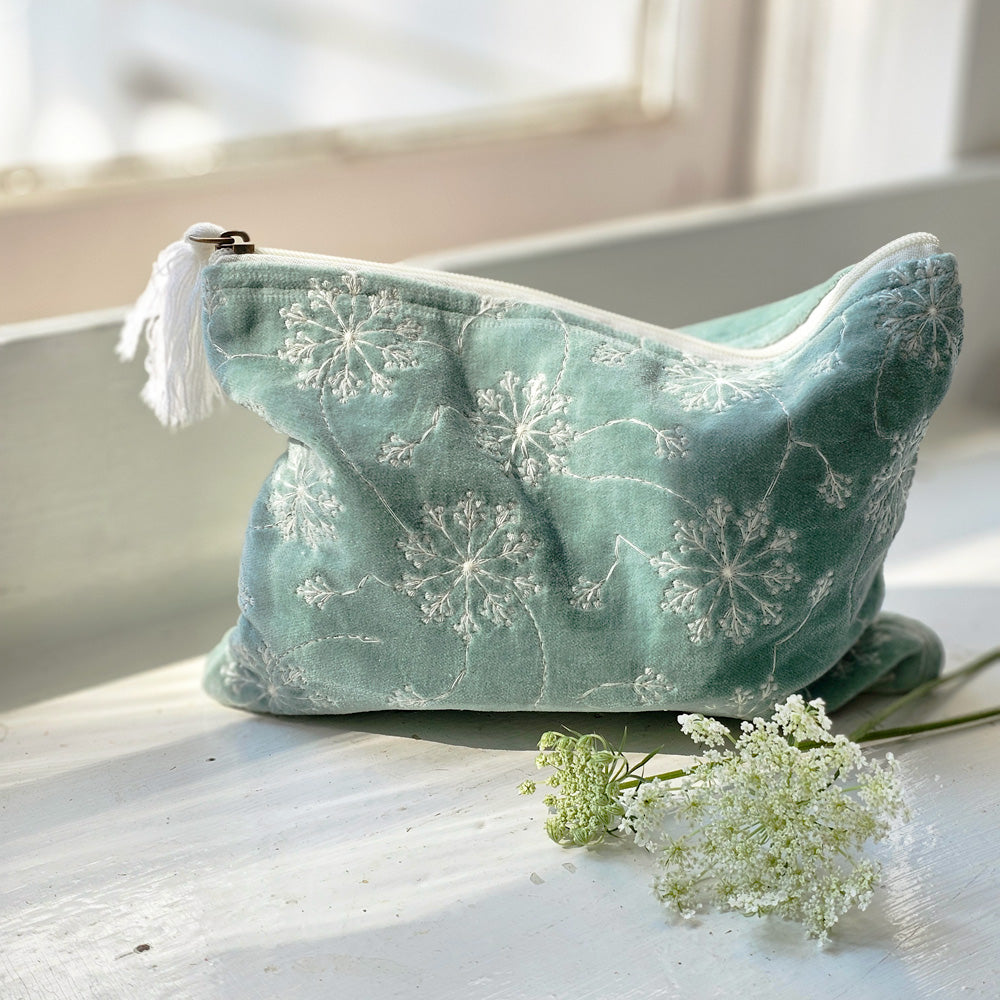 The Aqua Velvet Pouch with Queen Anne's Lace makes a pretty clutch for makeup and more. Available in two sizes, this stylish and functional zippered pouch features a dreamy light aqua velvet embroidered with a white Queen Anne's Lace flower design.  Select size in menu. Small: 8.25"L x 6.25"H, Large: 9.75"L x 7.25"H