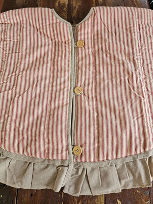 The Red Ticking Stripe Christmas Tree Skirt lends old-timey vintage charm to your holiday home. This 48" regular tree collar has a 100% cotton shell featuring a textured chambray striped pattern and ruffled border for that old-fashioned feel. The reverse side is a rustic farmhouse oatmeal, which gives it a flax linen feel. Wood buttons finish off this beautiful tree skirt.