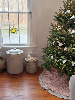 The Red Ticking Stripe Christmas Tree Skirt lends old-timey vintage charm to your holiday home. This 48" regular tree collar has a 100% cotton shell featuring a textured chambray striped pattern and ruffled border for that old-fashioned feel. The reverse side is a rustic farmhouse oatmeal, which gives it a flax linen feel. Wood buttons finish off this beautiful tree skirt.