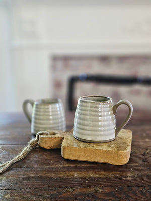 The Rustic Ribbed Stoneware Teacup Mugs (Teapot separately) feature a dreamy flax colored glaze over earthy stoneware. Hints of clay tones peek through the ribbed design. Each have a glazed-free, natural clay bottom and handle.This set of two cups bring an earthy elegance to your farmhouse kitchen. Tea Cup Mugs, Set of Two. Matching Teapot sold separately.