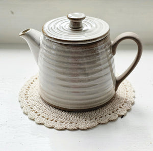 The Rustic Ribbed Stoneware Teapot (Teacups sold separately) features a dreamy flax colored glaze over earthy stoneware. Hints of clay tones peek through the ribbed design. Each have a glazed-free, natural clay bottom and handle.This stoneware teapot brings an earthy elegance to your farmhouse kitchen. Teapot only. Tea Cup, Set of Two sold separately.