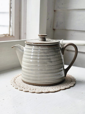 The Rustic Ribbed Stoneware Teapot and Teacups (each sold separately) feature a dreamy flax colored glaze over earthy stoneware. Hints of clay tones peek through the ribbed design. Each have a glazed-free, natural clay bottom and handle.The teapot and cups bring an earthy elegance to your farmhouse kitchen. Teapot and Tea Cup, Set of Two each sold separately.