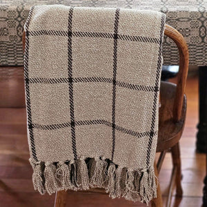 Get cozy and transform your favorite space with the refined style and complete comfort of this Rustic Black Windowpane Throw Blanket. This woven cotton throw features a black grid design on a rustic beige weave with tassels on top and bottom. This soft throw is perfect for creating a cozy home no matter the season. Crafted of 100% cotton, finished with a tassel edges, this throw is machine washable for easy care. 50"W x 60"H