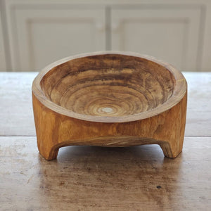 Add down-to-earth character to your farm table with our rustic Carved Wood Bowl with Legs. Inspired by the style of traditional hand-hewn dough bowls, this unique piece adds a touch of imperfection and charm. The decorative bowl is crafted from thick, carved wood and can be displayed year-round on a table, shelf, or counter. Each bowl is truly one-of-a-kind and complements any relaxed, rustic decor. Simply wipe clean with a dry cloth. Measures approximately 11.5” Diam x 4.75”H and varies in wood tone