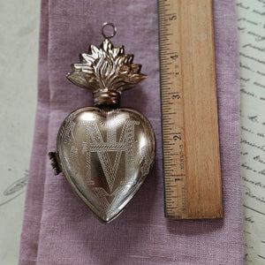 Introducing the Sacred Heart Locket Box, the perfect blend of vintage style and old-world charm. Crafted from aged metal with a golden bronze finish and intricate etchings, this locket box offers a timeless storage solution for your sacred treasures. Hang it from a chain or ribbon with the attached loop (Ribbon not included). A must-have for any collector.