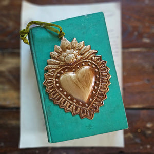 Our Sacred Heart Aged Gold Tin Ornament, with its distressed golden finish, evokes a sense of history, making it the perfect addition to any vintage-inspired decor. Handcrafted from aged metal with a rich, intricate design, this ornament exudes sophistication and old-world charm. Completed with a soft velvet ribbon for hanging, it is a must-have for any collector seeking exclusive and elegant treasures. 4.5" x 6"