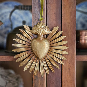 Introducing the Sacred Heart Rays of Light with a distressed golden finish. The Sacred Heart Rays of Light offers the perfect blend of vintage style and old-world charm. Crafted from aged metal with a golden aged finish and intricate etchings, this ornament offers a dramatic look for this sacred treasures. Includes velvet ribbon for hanging. A must-have for any collector. 7" x 7"