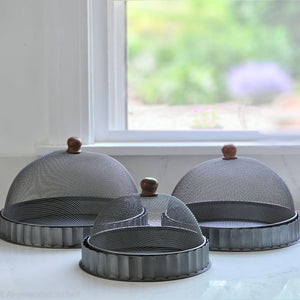 Keep bugs at bay on warm summer days with our Screen Food Covers with Metal Base, Set of Three . A wire mesh cloche, also known as a shoo-fly, is perfect for protecting food from flies and other insects. Our set of three Wire Mesh Food Covers has tons of vintage charm and offers a range of sizes. They feature aged metal base with scalloped edges. Add rustic elegance to your farmhouse kitchen or patio with our vintage style Screen Food Cover Cloches