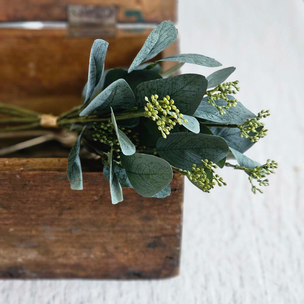 The Seeded Silver Dollar Eucalyptus Spray is a mix of dark blue-green faux eucalyptus leaves and seeds that adds rich texture and a moody elegance to any centerpiece. The spray is easily combined with other florals for a stunning centerpiece or displayed on its own. Includes one pick. 15"H