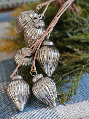 There's something magical about the way the light catches this Silver Mercury Glass Ornament Cluster. Inspired by vintage ornaments, this cluster of aged mirrored glass ornaments will add sparkle to any room. Features a cluster of six ribbed mercury glass ornaments handing from leather straps at various lengths. Each silver ornament is 1.5"diam x 2.75"H, 16"H overall. 