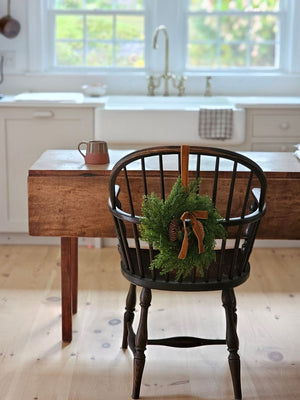The Small Cedar Wreath with Velvet Bow and Hanging Ribbon adds a refined touch to kitchen cabinets, windows, and cupboards. Crafted with realistic faux cedar foliage and pinecones, it brings understated elegance to any space. Finished with a plush velvet bow and an attached ribbon, this wreath offers effortless and graceful hanging. 13" Diam
