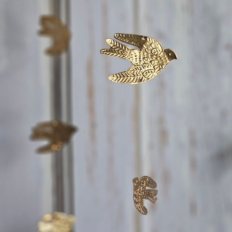 Add a magical touch to any room with our Golden Bird Mobile. The small tin doves appear to float in the air as they hang from golden wires. Features a golden velvet ribbon for hanging.