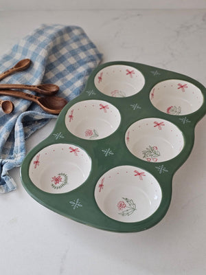 Whether you're baking up something sweet or savory, this Stoneware Muffin Pan with Cottage Style is sure to elevate any recipe. The floral print baking dish holds six muffins or cupcakes. It features a dark sage green base with sweet pink cottage flower graphics in each muffin cup. Dishwasher safe. 12"L x 7.5"W x 1.5"H