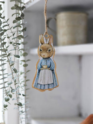 Inspired by Peter Rabbit's mom, this Tea Time Rabbit Ornament lends fairy tale cottage charm to any room. Wearing a classic cottage apron, this bunny is ready for a tea time break. Hang from a hook or from a basket full of your favorite flowers. Image featured on each side of the ornament. 2"L x 4"H