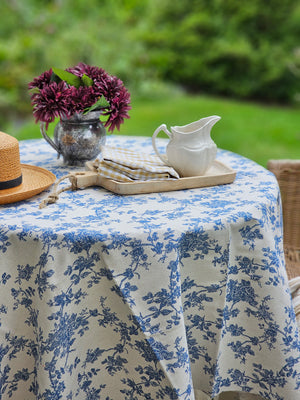 Our Toile Fabric-Blue Flowers adds instant French Country cottage charm. Features a rich blue floral toile design on a rustic oatmeal background. This fabric can be used to make pillows and more, but we love it simply as a no-sew tablecloth (doesn't have a stitched hem) for casual country style. Layer with other tablecloths to create a cozy farmhouse feel. Perfect for café tables or small square table that seat 2-4. 100% Cotton. Hand wash. Line dry. 59” x 59”   