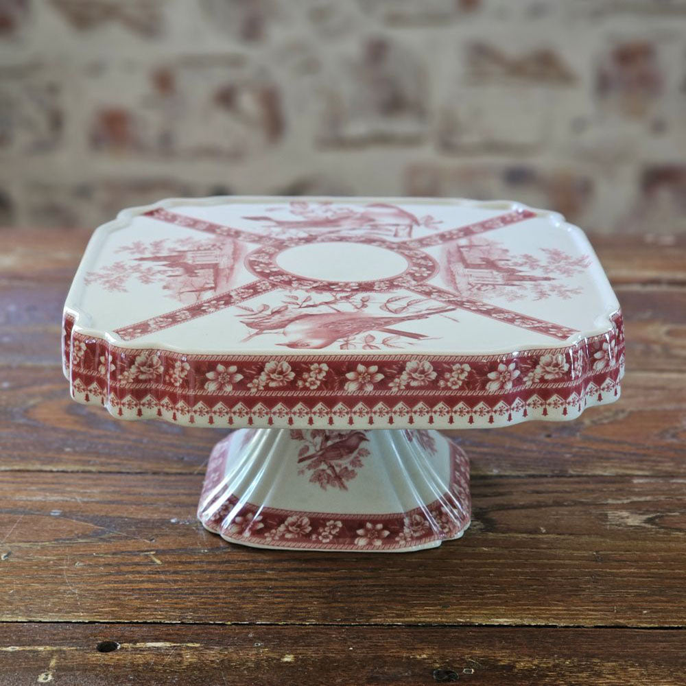 The Transferware Cake Stand brings elegant French country charm to your home with its timeless design. Crafted from fine porcelain, this square stand showcases a delicate bird and floral pattern on an off-white background, perfect for presenting desserts or enhancing your decor. Measuring 8.25" square by 3.75" high, it blends vintage heritage with refined sophistication.