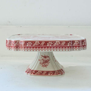 The Transferware Cake Stand brings elegant French country charm to your home with its timeless design. Crafted from fine porcelain, this square stand showcases a delicate bird and floral pattern on an off-white background, perfect for presenting desserts or enhancing your decor. Measuring 8.25" square by 3.75" high, it blends vintage heritage with refined sophistication.