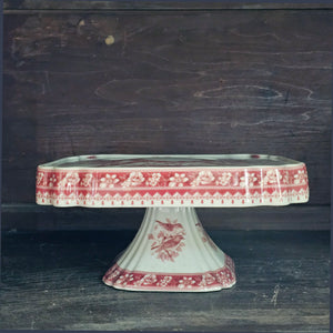 The Transferware Cake Stand brings elegant French country charm to your home with its timeless design. Crafted from fine porcelain, this square stand showcases a delicate bird and floral pattern on an off-white background, perfect for presenting desserts or enhancing your decor. Measuring 8.25" square by 3.75" high, it blends vintage heritage with refined sophistication.