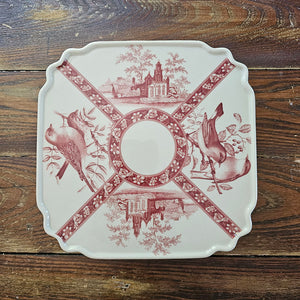 The Transferware Cake Stand brings elegant French country charm to your home with its timeless design. Crafted from fine porcelain, this square stand showcases a delicate bird and floral pattern on an off-white background, perfect for presenting desserts or enhancing your decor. Measuring 8.25" square by 3.75" high, it blends vintage heritage with refined sophistication.
