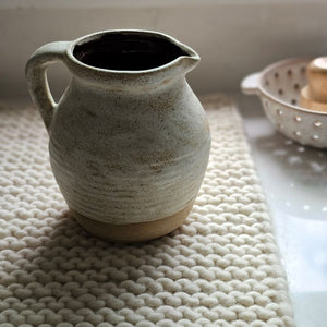 Our Tudor Farm Kitchen Pitcher embodies an old farmhouse aesthetic and Wabi Sabi philosophy—celebrating imperfection, simplicity, impermanence, nature, and uniqueness. Perfect for adding artisanal elegance to any setting. Features a rustic oatmeal color glaze with a natural, non-glazed bottom for an antique and timeless look. Decorative use only. 