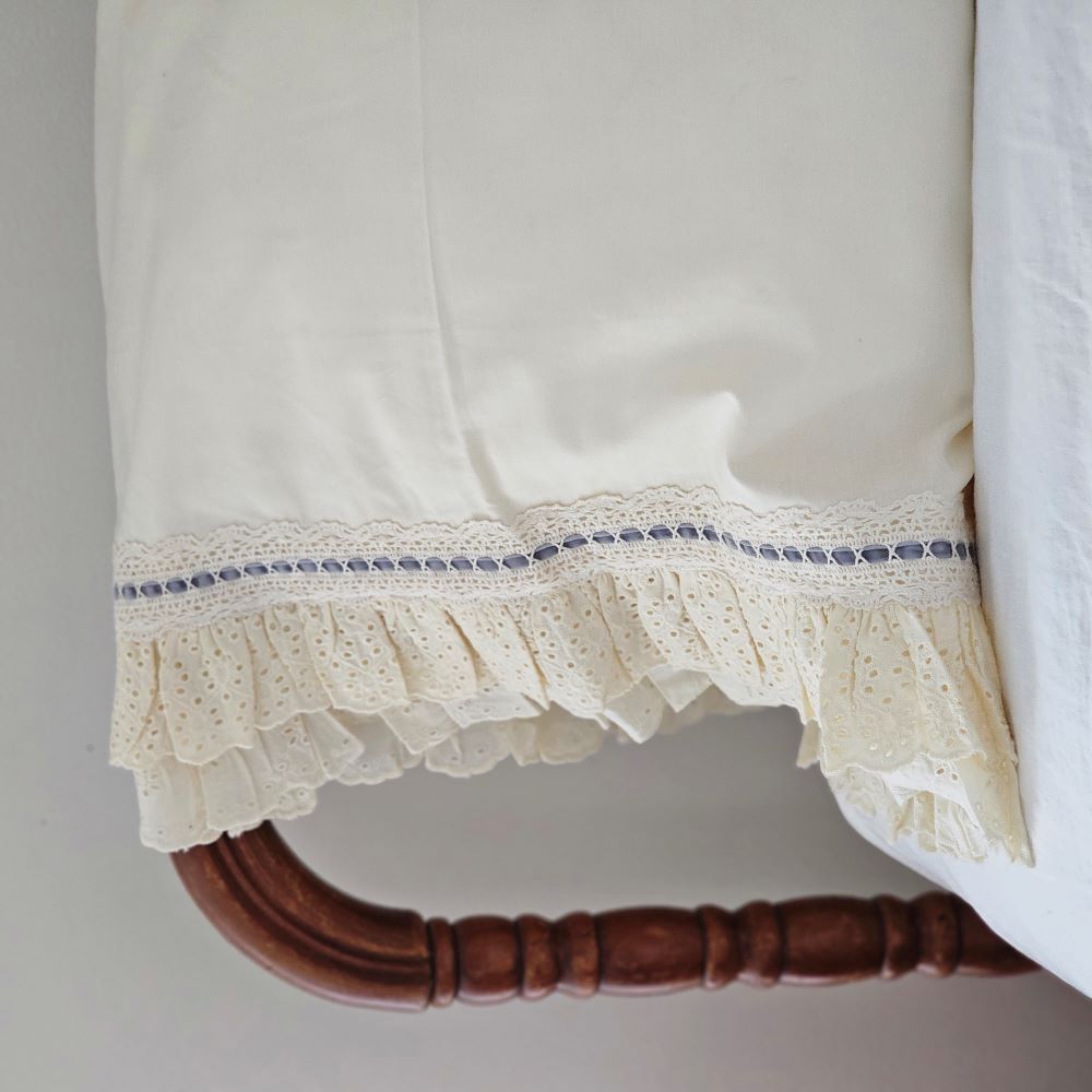 Our Eyelet Ruffles with Velvet Ribbon Pillowcase, Set of Two lends dreamy cottage style to any bedroom. These cream pillowcases feature a double layer of ruffle edges with exquisite floral eyelet detail with a grey blue velvet ribbon woven through a crochet border. This lace edge pillowcase will add texture and a charming vintage look to your room.