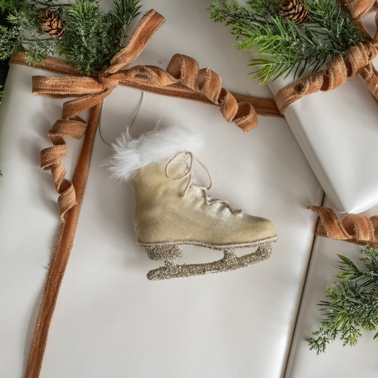 This Velvet Ice Skate Ornament brings a festive touch to any holiday decor. Its old-timey design features a silver sparkle skate, creamy-beige fur, and a fluffy white fur collar. Show off your winter wonderland style with this unique ornament for your tree, wreaths, or use as a gift-topper. 4.25"L