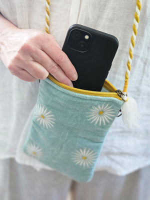 The Velvet Sling Bag with Daisies makes a pretty carry bag for your phone, glasses, keys and more. This stylish and functional zippered pouch features a dreamy light aqua velvet embroidered with a white daisy flower design. It also features a removable mustard yellow and white rope strap with clasp. 6"L x 10"H
