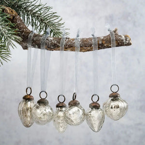 Our Vintage Crackle Glass Bulb Ornaments Mixed Designs come as a set of six different designs. These small hand-blown glass ornaments are inspired by vintage mercury glass bulbs. The glass bauble has a crackle glaze that is applied to the exterior when initially blown. This gives the glass an aged, crackled look. Each bulb is topped with an ornately detailed bronzed colored cap and finished with an organza ribbon for hanging. Each approximately 1.18” Diam.