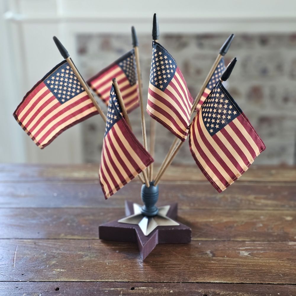 Celebrate patriotic style with our Vintage Americana Finial Flag Holder with vintage style USA Flags. The star-shaped wood finial comes with six vintage style American flags and will brighten any room in your farmhouse all year long. Each flag has an aged-tea-stained patina to add vintage charm. Finial is 6.5" in diameter. Flags are 12.5"H. Overall 16"H with flags in finial.