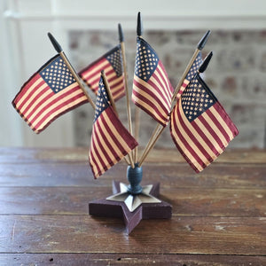 Celebrate patriotic style with our Vintage Americana Finial Flag Holder with vintage style USA Flags. The star-shaped wood finial comes with six vintage style American flags and will brighten any room in your farmhouse all year long. Each flag has an aged-tea-stained patina to add vintage charm. Finial is 6.5" in diameter. Flags are 12.5"H. Overall 16"H with flags in finial.