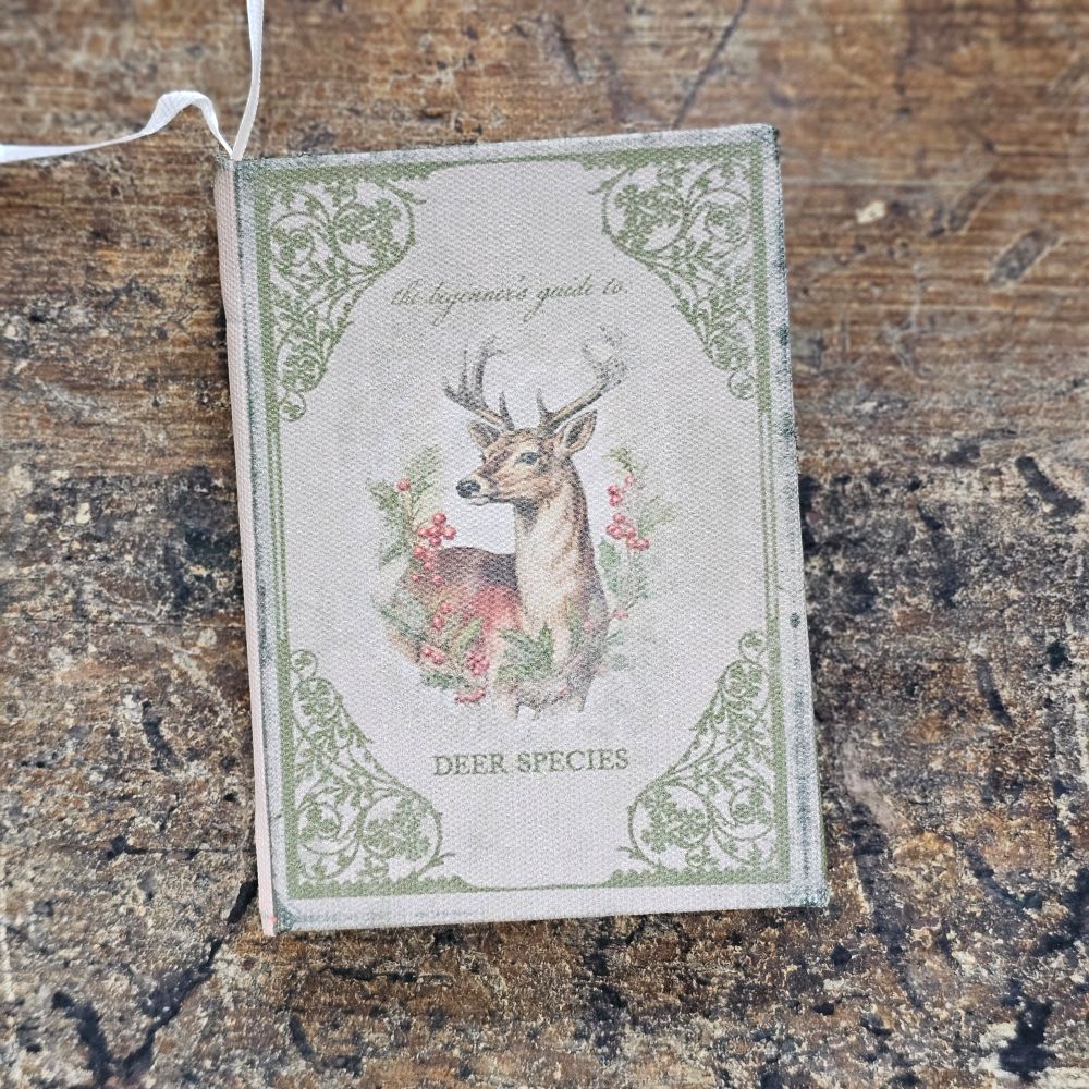 The Vintage Book Journal Ornament with Deer Cover is inspired by antique bookshop finds. This ornament is a hardcover journal with a faded cover featuring a deer with antlers and aged paper pages inside that can actually be used for note keeping. It's infused with vintage charm. Makes a sweet gift-topper.