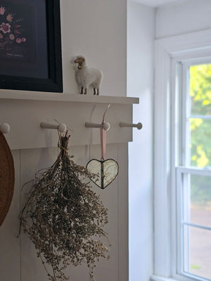 This sweet Vintage Lace Heart ornament captures romantic charm through delicate lace suspended between hand-soldered glass panels. The weathered antique metal frame adds authentic vintage character, while a luxurious satin ribbon provides an elegant finishing touch. Perfect for treasured collections or as a meaningful gift. Lace will vary with each heart, as no two are alike.