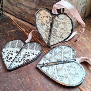 This sweet Vintage Lace Heart ornament captures romantic charm through delicate lace suspended between hand-soldered glass panels. The weathered antique metal frame adds authentic vintage character, while a luxurious satin ribbon provides an elegant finishing touch. Perfect for treasured collections or as a meaningful gift. Lace will vary with each heart, as no two are alike.