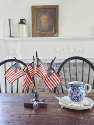 Celebrate patriotic style with our Vintage Americana Finial Flag Holder with vintage style USA Flags. The star-shaped wood finial comes with six vintage style American flags and will brighten any room in your farmhouse all year long. Each flag has an aged-tea-stained patina to add vintage charm. Finial is 6.5" in diameter. Flags are 12.5"H. Overall 16"H with flags in finial.