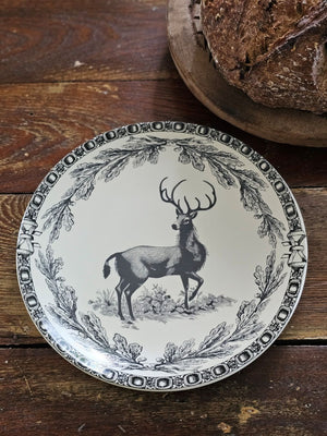 This stoneware Vintage Style Deer Plate features an elegant deer motif framed by delicate branch and acorn patterns, inspired by timeless old-world decor. Antique white with black details, it has a coordinating border design adds a refined touch, making it ideal for both everyday meals and special seasonal gatherings. Crafted for convenience, the plate is microwave, oven, dishwasher, and food safe, blending rustic charm with practical functionality. Includes one plate. 8" diam