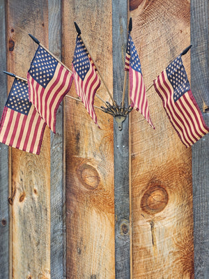 Celebrate patriotic style with our Wall Mount Flag Holder with Flags. This cast iron wall bracket comes with five vintage style American flags and will brighten any room in your farmhouse all year long. Hang it by the front door or porch or let those flags wave proudly in any room. Each flag has an aged-tea-stained patina to add vintage charm. Bracket is 4.75" without flags and 28" wide with flags