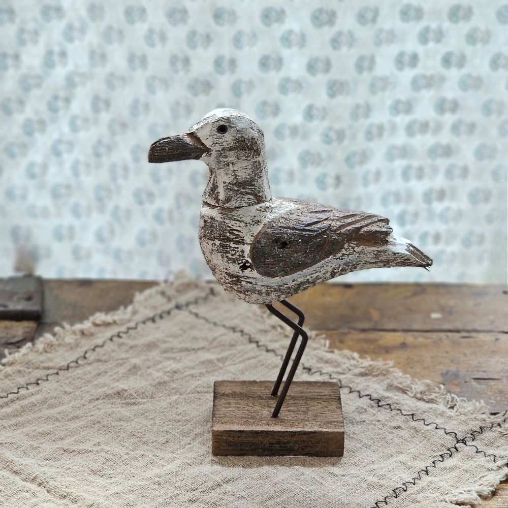 Our Weathered Wood Seagull Shelf Sitter is inspired by weather-worn driftwood designs. This seagull, a classic seaside icon, is made of natural wood with white painted accents and distressed details. Decorative seagull sits on metal stakes resembling bird legs attached to a wood base. Our white seagull sitter is designed to free-stand on any flat surface making it easy to display. A rustic beach-themed home accent that coordinates well with primitive home decor.
