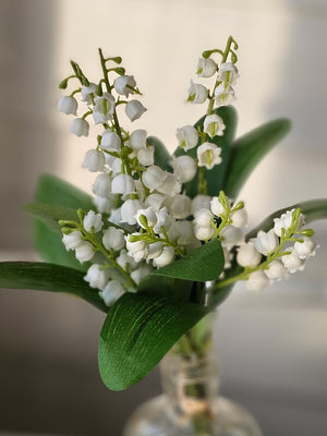 The White Bell Flower Bouquet has all the&nbsp; lovely qualities of Lily of the Valley. These dainty faux bell flowers really pop against their fresh green leaves. Each bouquet includes three stems bursting with flowers and tied in raffia. Approximately 13"H