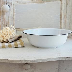This vintage style White Enamelware Basin is sturdy and dependable.  Inspired by 1940s-style enamelware wash basins, this bowl gives any kitchen an old country farmhouse feel. Features aged white finish with black trim. This enamelware has been slightly distressed for an aged appearance and chips to the enamel and other imperfections are a natural part of the aging process. Not food safe. 11” Diam x 4”H