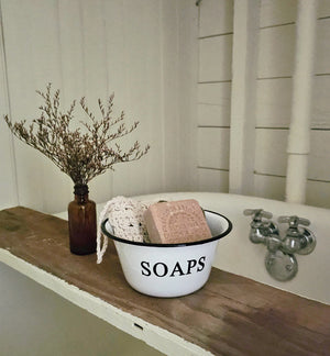 Our White Enamel Soap Bowl has a nostalgic quality that's perfect for a vintage style bathroom or guest room. The distressed white enamelware with black trim is classic farmhouse style. (Soaps and Brush Not Included.) 6" Diam x 3"H