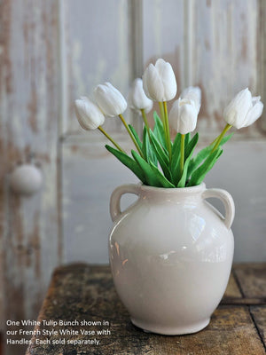 White tulips in a French-style white vase with handles.