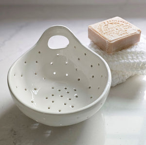 The White Ceramic Berry Bowl Colander offers relaxed farmhouse style. It's perfect for washing berries and fruit. It also makes an ideal soap and sponge holder as the holes allow air to circulate and dry and prevent mildew.&nbsp; It features a handle so it can be hung from a peg rail with ease.&nbsp; 6"Diam x 2.75"H