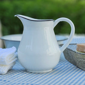 Bring the easy charm of country cottage living to your farmhouse with our White Enamel Pitcher with black rim. The simple allure of enamelware fits right in with any decor, but every farmhouse needs at least one piece. Inspired by flea market finds, our vintage style white enamel pitcher has black trim and makes the perfect vase for your favorite bouquet. Not food safe. Pitcher measures 7.5" H x 8" W (with handle) x 4.5" Diam