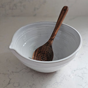 The White Farmhouse Mixing Bowl has a clean, simple design that will help you whip up a farmhouse style pancake breakfast and other goodies. It features a rustic hand-thrown pottery look with pour spout. The whitewash glaze and unglazed bottom add to its rustic feel. This sturdy bowl is perfect for every day living. Food safe. Hand wash recommended. Wood spoon sold separately. 9.5" Diam x 4.75"H