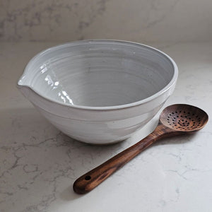 The White Farmhouse Mixing Bowl has a clean, simple design that will help you whip up a farmhouse style pancake breakfast and other goodies. It features a rustic hand-thrown pottery look with pour spout. The whitewash glaze and unglazed bottom add to its rustic feel. This sturdy bowl is perfect for every day living. Food safe. Hand wash recommended. Wood spoon sold separately. 9.5" Diam x 4.75"H