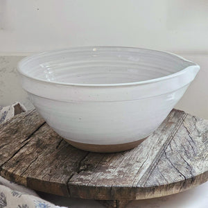 The White Farmhouse Mixing Bowl has a clean, simple design that will help you whip up a farmhouse style pancake breakfast and other goodies. It features a rustic hand-thrown pottery look with pour spout. The whitewash glaze and unglazed bottom add to its rustic feel. This sturdy bowl is perfect for every day living. Food safe. Hand wash recommended. Wood spoon sold separately. 9.5" Diam x 4.75"H