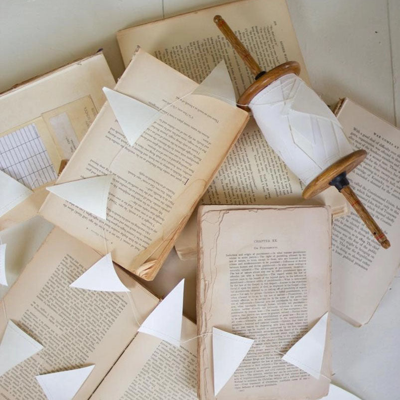 Make it a celebration all year long with our White Paper Flag Garland On Wood Spool. Features 27 yards of white paper flag garland on a vintage style wood spool. Decorate for a bridal shower, birthday, or add English cottage style to bedrooms and fire place mantles. My favorite application is styling it on a Christmas tree with a few white candle lights. Each white flag is 2" x 3.25"H. 27 yards