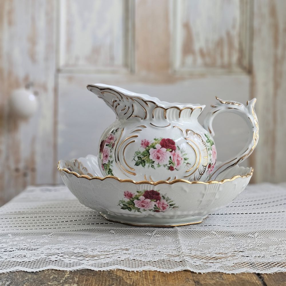 The Porcelain White Pitcher and Bowl with Vintage Rose and Gold Accents is an elegant set that brings timeless sophistication to your table. Crafted from high-quality porcelain with a smooth, glossy finish, this set combines durability with refined aesthetics. The pitcher features an easy-pour spout and gracefully curved handle, while the matching bowl also features a rose design in the center. 