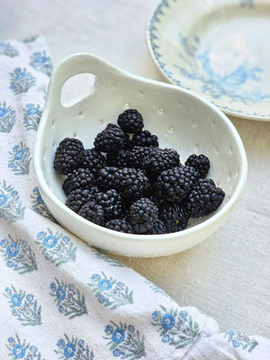 The White Ceramic Berry Bowl Colander offers relaxed farmhouse style. It's perfect for washing berries and fruit. It also makes an ideal soap and sponge holder as the holes allow air to circulate and prevent mildew.&nbsp; It features a handle so it can be hung from a peg rail with ease.