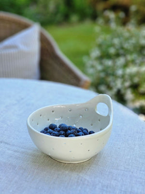 The White Ceramic Berry Bowl Colander offers relaxed farmhouse style. It's perfect for washing berries and fruit. It also makes an ideal soap and sponge holder as the holes allow air to circulate and dry and prevent mildew.&nbsp; It features a handle so it can be hung from a peg rail with ease.&nbsp; 6"Diam x 2.75"H